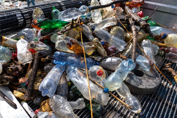 Pile of discarded plastic bottles and debris tangled on a metal surface, illustrating plastic pollution.