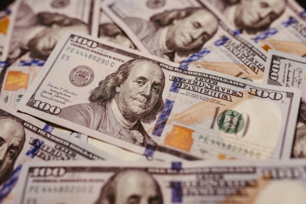 Pile of U.S. hundred-dollar bills overlapping on a surface
