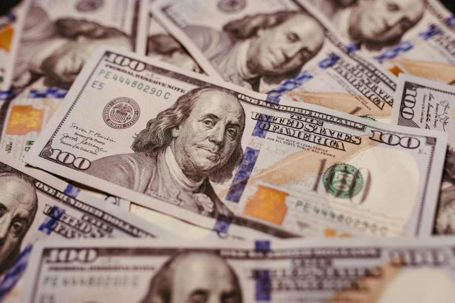 Pile of U.S. hundred-dollar bills overlapping on a surface