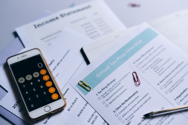 Close-up of tax documents and forms on a desk, with a smartphone and a pen nearby.