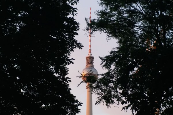A captivating view of the Berlin TV Tower framed by trees during a beautiful sunset in Germany.