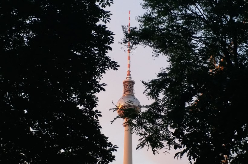 A captivating view of the Berlin TV Tower framed by trees during a beautiful sunset in Germany.